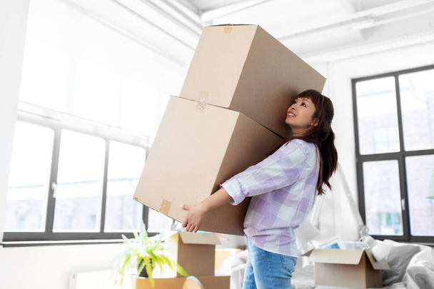 gelukkig vrouw holding dozen en verhuizen naar nieuw huis - Foto, afbeelding