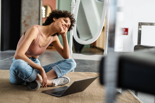 White young woman using laptop computer while sitting on a floor in the modern living room - Foto, imagen
