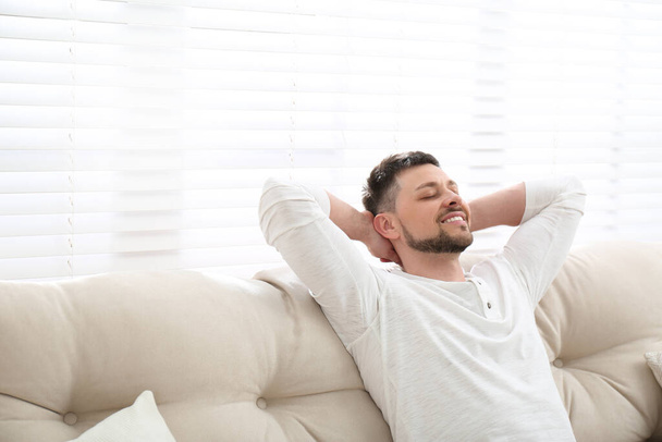 Handsome man relaxing on sofa, space for text - Foto, Bild