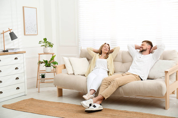 Couple relaxing on sofa in living room - Фото, изображение