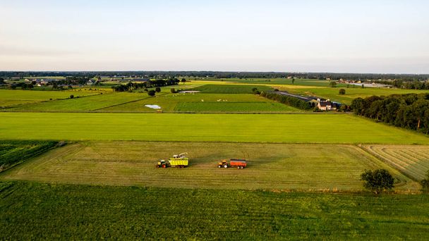 Εναέρια του χορτοδετικό τρακτέρ που παράγει άχυρα σε αγρούς μετά τη συγκομιδή σιταριού το καλοκαίρι στην εκμετάλλευση - Φωτογραφία, εικόνα