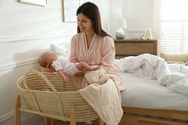 Happy young mother with her cute newborn baby in bedroom - Foto, imagen