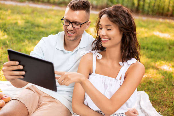 couple heureux avec tablette pc au pique-nique dans le parc - Photo, image