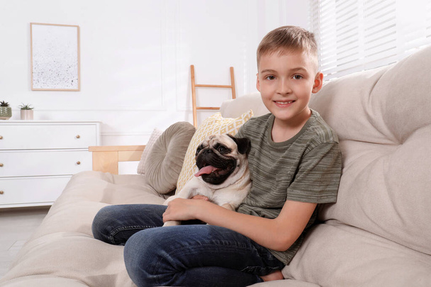 Boy with his cute pug on sofa at home. Space for text - Foto, afbeelding