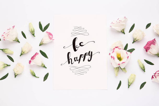 Frame of beautiful flowers and paper card with handwritten text Be happy on white background, flat lay - Zdjęcie, obraz