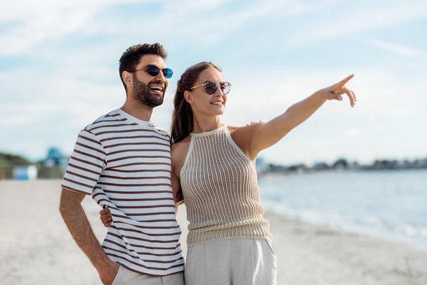 happy couple pointing finger on summer beach - Zdjęcie, obraz