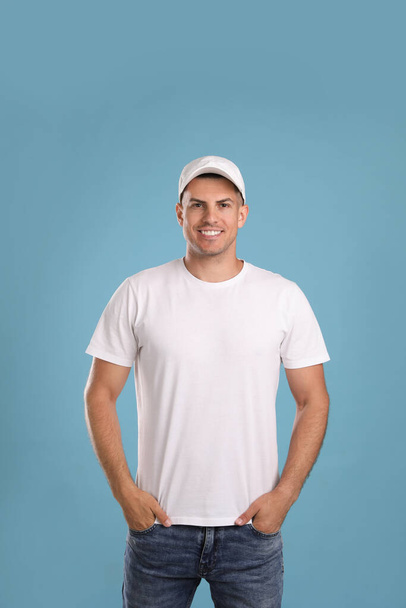 Happy man in white cap and tshirt on light blue background. Mockup for design - Photo, Image