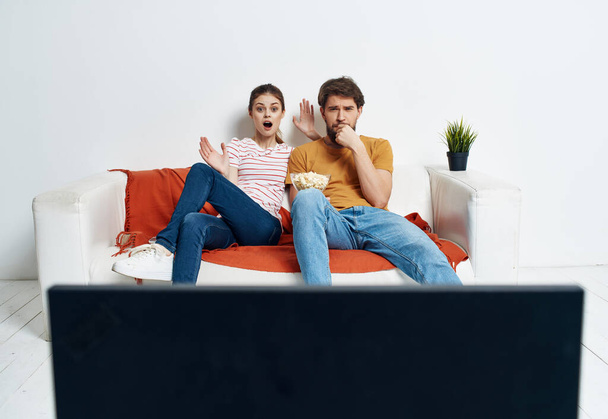 young couple sitting on the couch popcorn watching a movie relaxing - Fotó, kép
