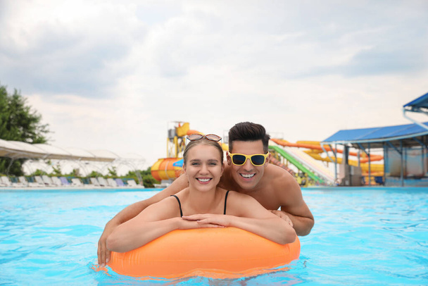 Szczęśliwa para z nadmuchiwanym pierścieniem w basenie w parku wodnym - Zdjęcie, obraz