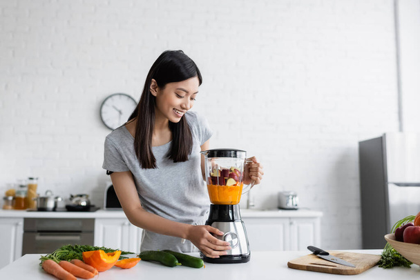 happy asian woman preparing fresh smoothie for breakfast in kitchen - Foto, Imagem