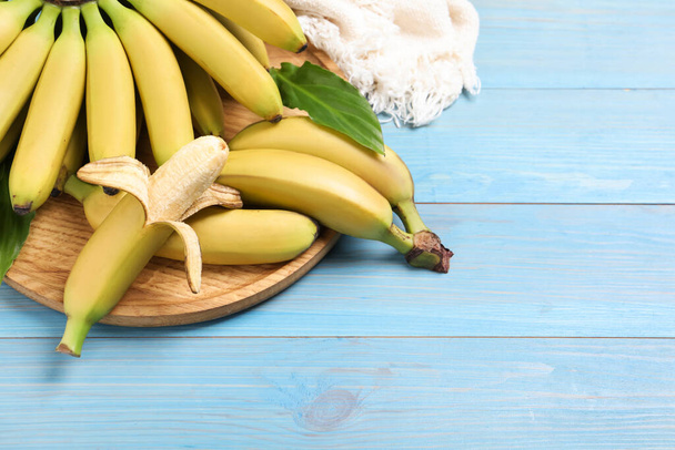 Tasty ripe baby bananas on light blue wooden table - Foto, Imagen