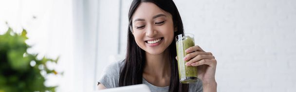pretty asian woman smiling while holding glass of delicious smoothie, banner - Foto, immagini