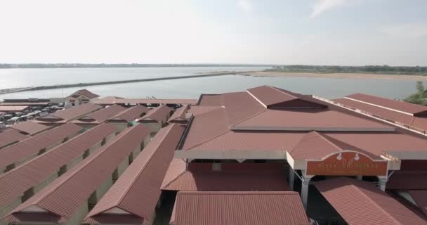 aerial silding shot of roofs of the local market. Bamboo bridge as backdrop - Filmati, video