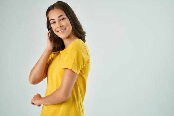 mooi brunette houden haar haar geel t-shirt mode moderne stijl - Foto, afbeelding