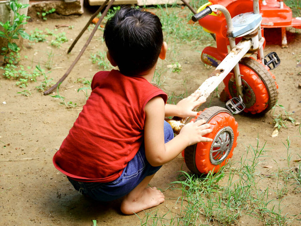 Gyerekek javítás játék kerékpár zöld fű talaj területén. - Fotó, kép