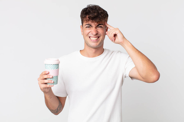 young handsome man feeling confused and puzzled, showing you are insane and holding a take away coffee - Fotoğraf, Görsel