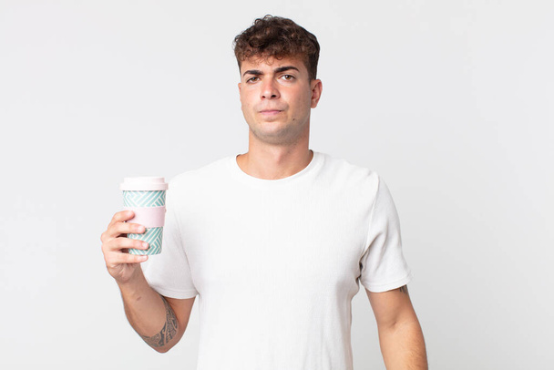 young handsome man feeling sad, upset or angry and looking to the side and holding a take away coffee - Foto, Imagen