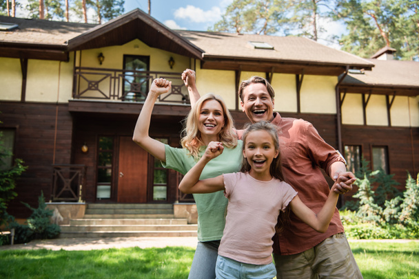 Excited family showing yes gesture near vacation house  - Photo, Image