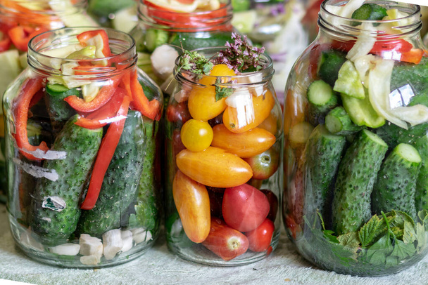 Glasgefäße mit verschiedenen Farben, Arten, Gemüseformen, Gemüse, das für die Konserven zu Hause zubereitet wird, Herbsterntezeit, Herbst - Foto, Bild