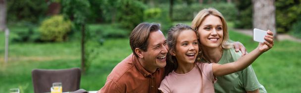 Smiling girl talking selfie with parents outdoors, banner  - Valokuva, kuva