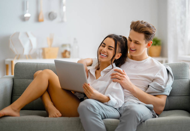 Young couple is using laptop. Woman and man having fun staying at home. - Foto, immagini