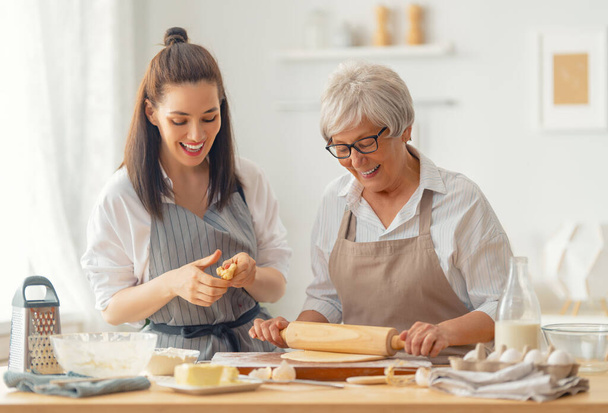 Happy family in the kitchen. Mother and her adult daughter are preparing pastry. - 写真・画像