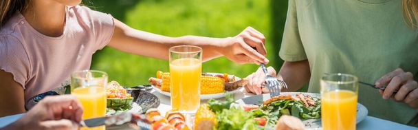 Cropped view of kid holding fork near salad and parents outdoors, banner  - Fotografie, Obrázek