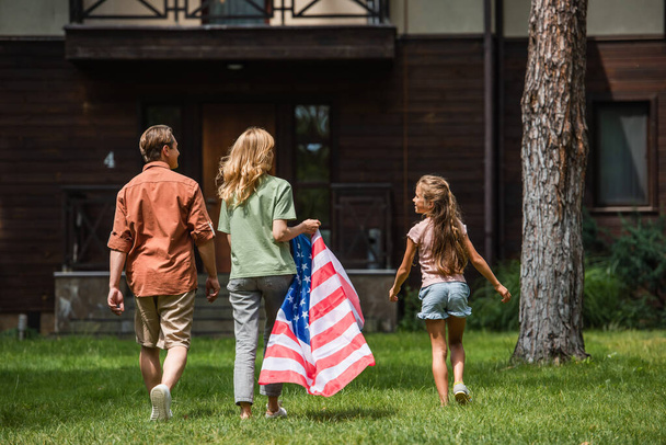 Kid and parents with american flag walking on lawn  - Foto, immagini