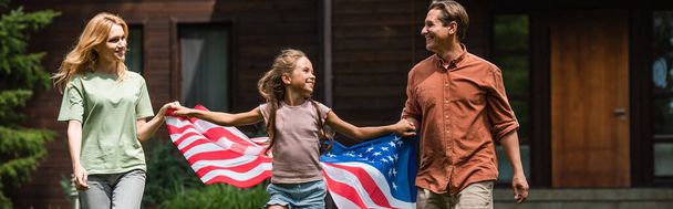 Kid and parents with american flag holding hands outdoors, banner  - 写真・画像
