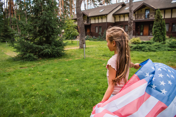 Girl holding american flag on lawn outdoors  - Фото, зображення