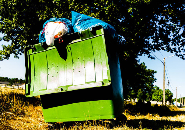 заполненный мусорный бак для переполнения с мешками, выходящими на вершину без возможности закрытия крышки - Фото, изображение