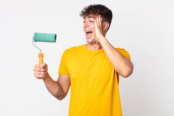 young handsome man feeling happy, excited and surprised. painting home concept - 写真・画像