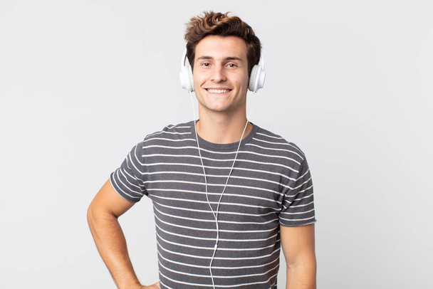 young handsome man smiling happily with a hand on hip and confident. listening music concept - Foto, immagini