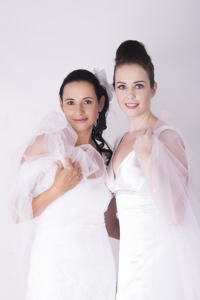 Великолепные невесты носят белые свадебные платья улыбаясь
 - Фото, изображение