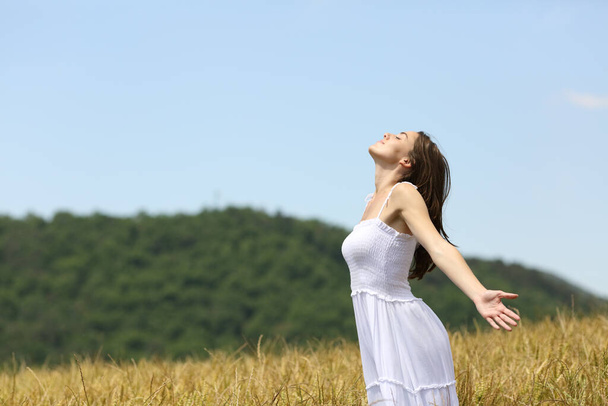 Profile of a woman breathing fresh air in a wheat field on summer - Photo, Image