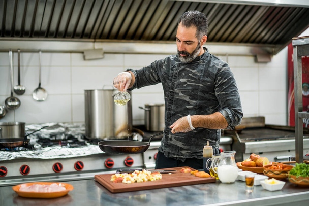 Profesyonel aşçı restoranın mutfağında yemek hazırlıyor. Et kızartmadan önce tavayı yağlıyor.. - Fotoğraf, Görsel