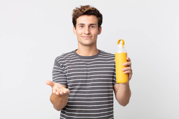 young handsome man smiling happily with friendly and  offering and showing a concept and holding a coffee thermos - Foto, Imagem
