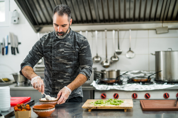 Professioneller Koch serviert Mahlzeit in der Küche des Restaurants. - Foto, Bild