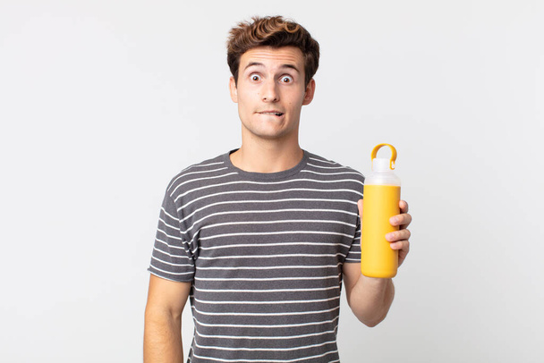 young handsome man looking puzzled and confused and holding a coffee thermos - Foto, afbeelding
