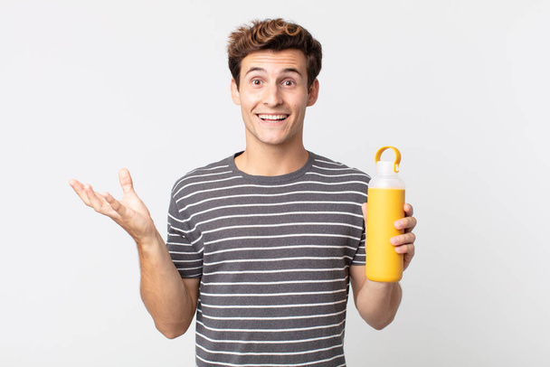 young handsome man feeling happy, surprised realizing a solution or idea and holding a coffee thermos - Foto, Imagem