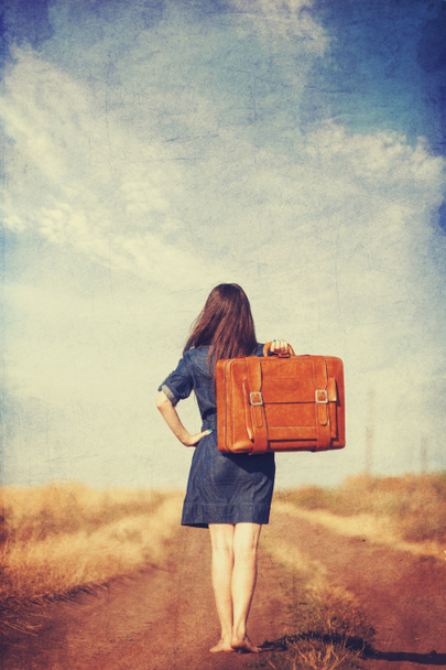 Брюнетка с чемоданом на сельской дороге
. - Фото, изображение