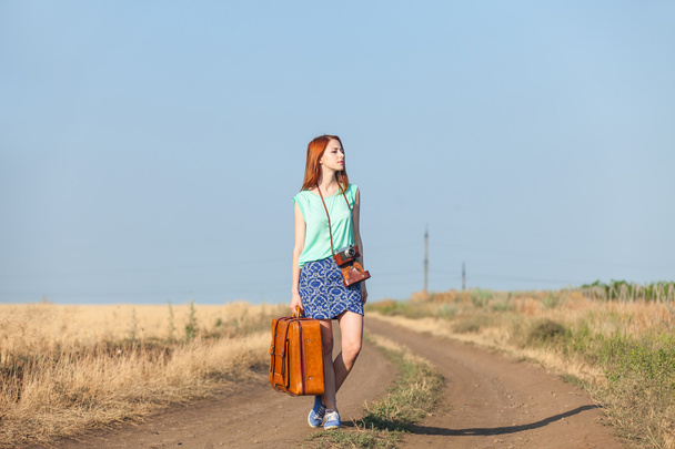 Redhead girl with suitcase on country road. - Fotografie, Obrázek