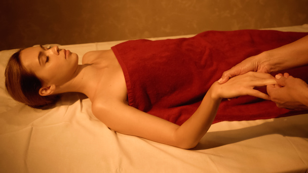 jovem cliente com olhos fechados recebendo massagem manual do massagista no salão de spa - Foto, Imagem