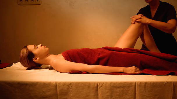 zijaanzicht van jonge vrouw ontvangen been massage van professionele masseur  - Foto, afbeelding