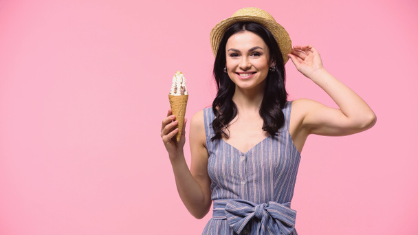 Cheerful woman in sun hat holding ice cream and looking at camera isolated on pink  - Foto, immagini
