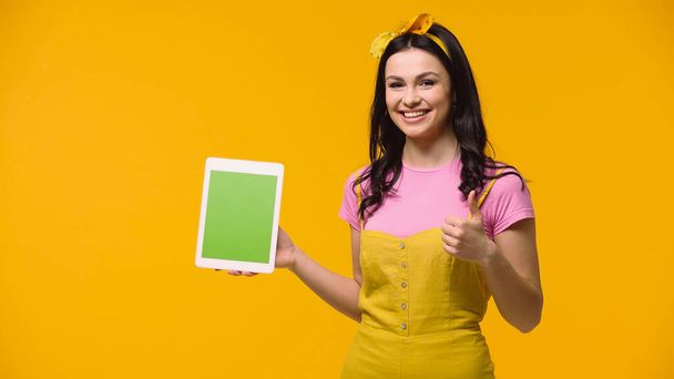 Positive woman showing like while holding digital tablet with chroma key isolated on yellow - Foto, afbeelding