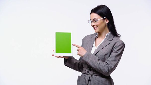 Glimlachende zakenvrouw wijst naar digitale tablet met chroma sleutel geïsoleerd op wit - Foto, afbeelding
