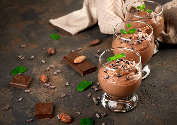 Vegan chocolate mousse with mint, bar of chocolate and cocoa beans on a dark background. Copy space - Photo, Image