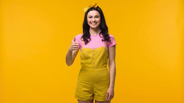 Junge lächelnde Frau zeigt sich wie isoliert auf gelb - Foto, Bild