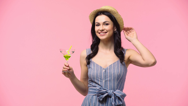 Donna sorridente in cappello solare con cocktail isolato su rosa  - Foto, immagini